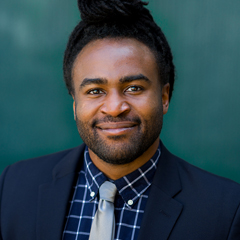 Photo of a choral student wearing a suit and smiling indoors.