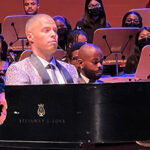 Photo of Lenny Hayes performing piano on stage in concert attire