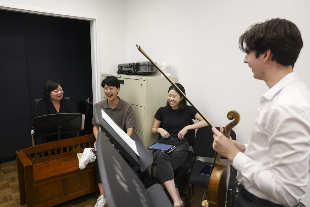 Photo of Yura Lee teaching a group of violin students