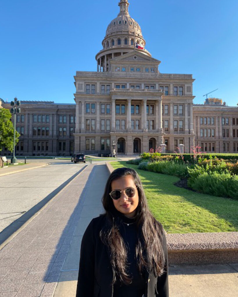 Photo of a young woman wearing sunglasses outside the state capitol building in Texas.