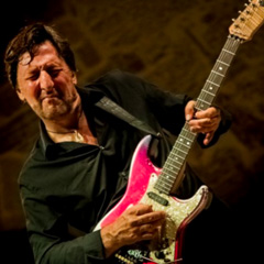 Photo of Richard Smith playing a red electric guitar.
