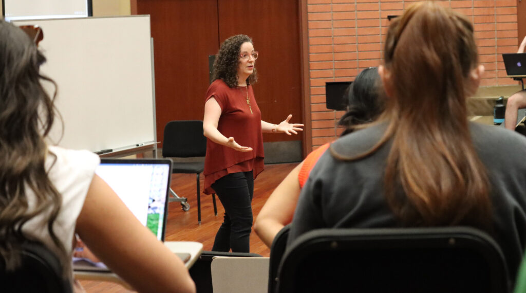 A teacher instructing a large classroom indoors.