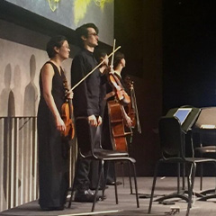 Photo of musicians holding classical string instruments on stage.