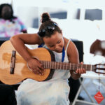 A young person plays an acoustic guitar.
