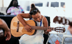 A young person plays an acoustic guitar.