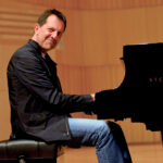 Photo of pianist Alan Pasqua sitting at a piano.