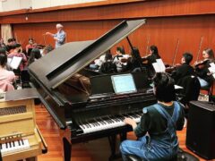 Photo of pianist performing in a rehearsal with an orchestra.