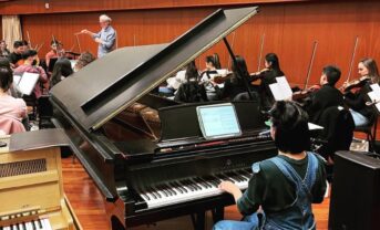 Photo of pianist performing in a rehearsal with an orchestra.