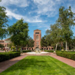 USC Bovard Auditorium exterior featuring lawn and fountain.