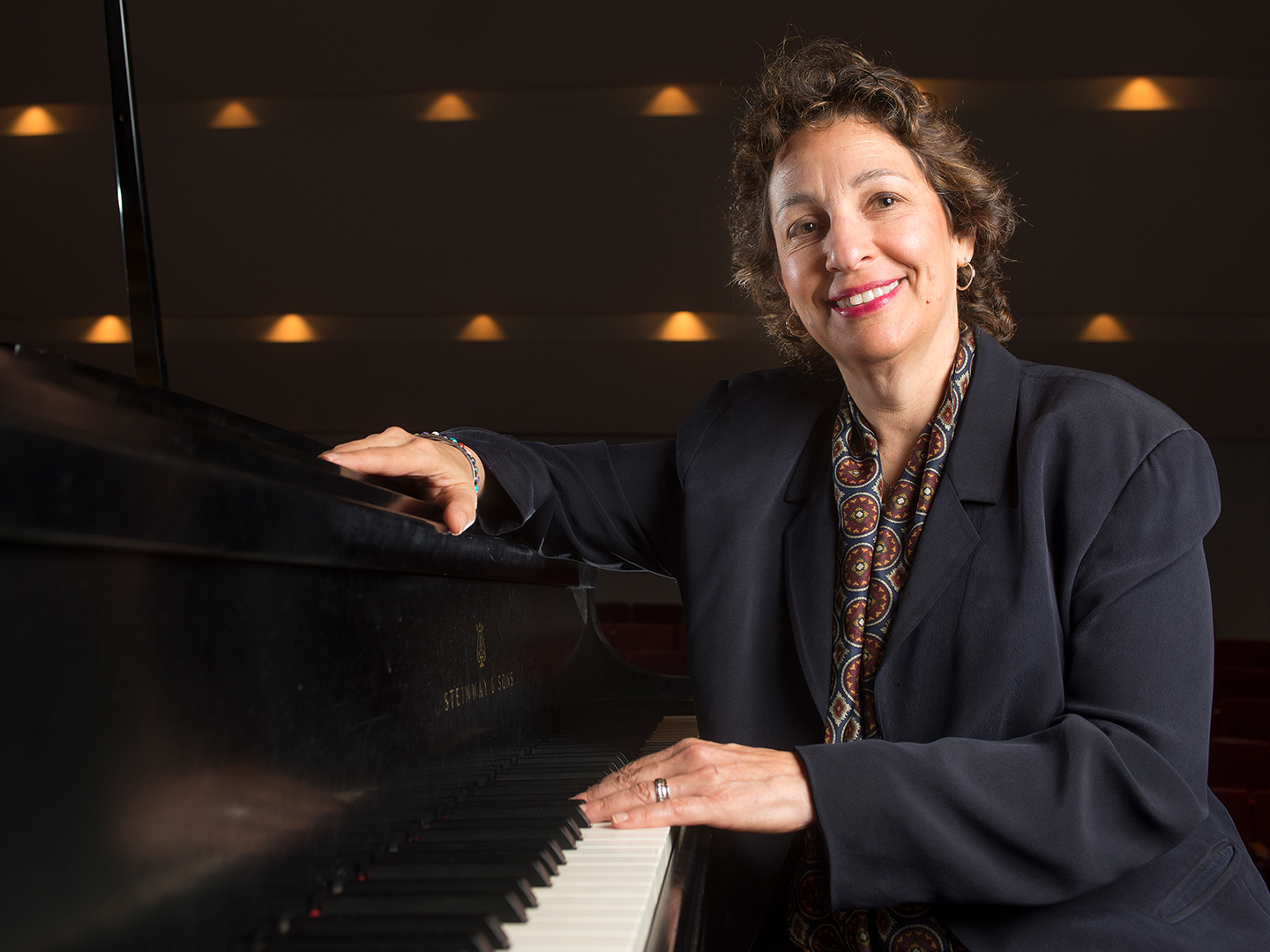 Dr. Iris Levine wearing a black blazer, seated at a piano. 