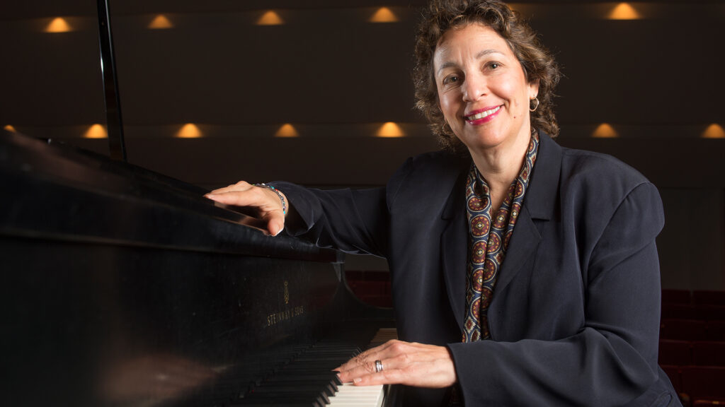 Photo of Dr. Iris S. Levine sitting at a piano smiling.