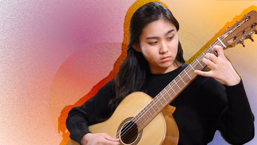 A classical guitarist plays her instrument in front of a brightly colored artistic background.