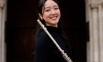 Photo of a flutist holding her instrument outside.