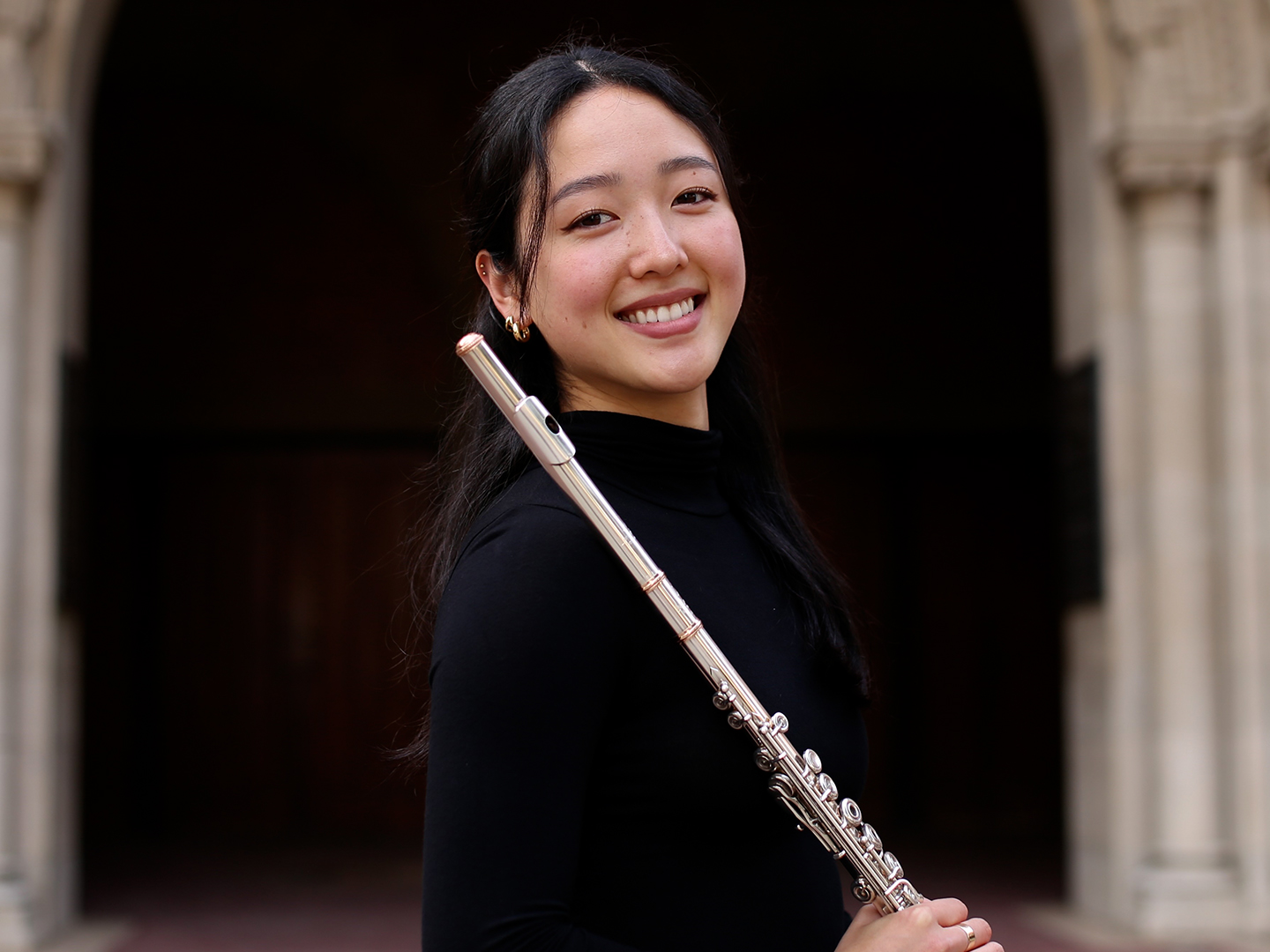 Flutist Julie Kim holding her instrument outside. 