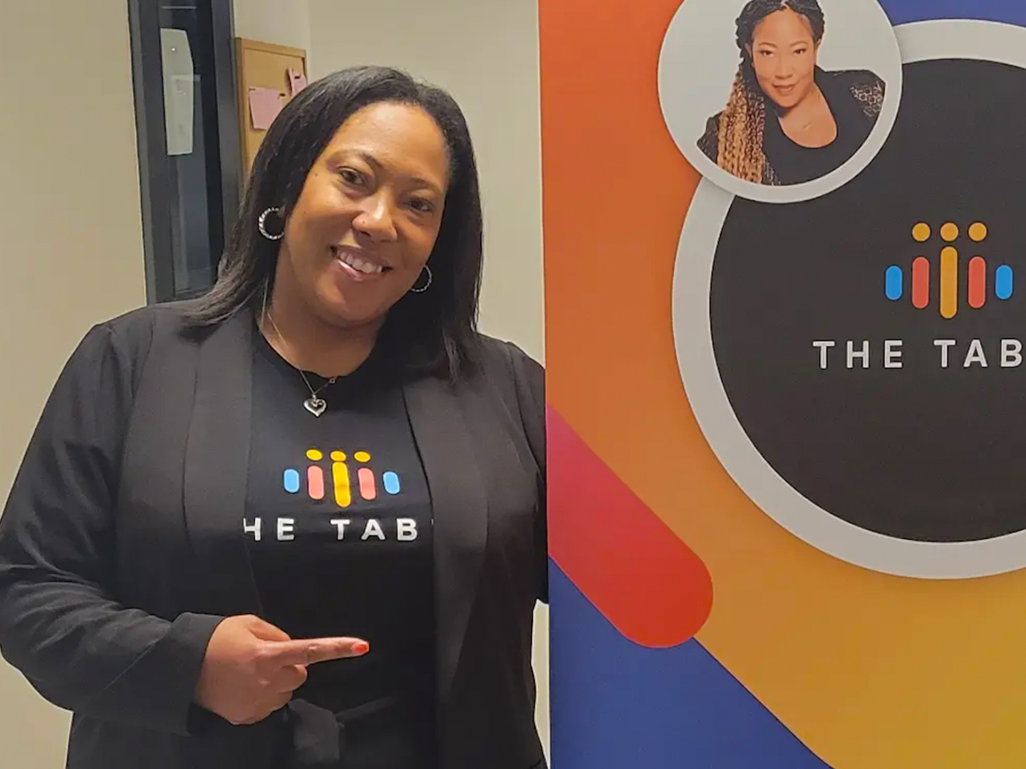 Angelica Brooks standing next to a colorful banner indoors. 