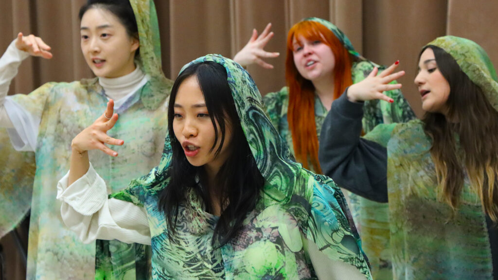 Photo of opera students rehearsing in green costumes.