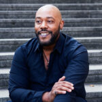 Photo of Derrick Lawrence smiling on an outdoor staircase.