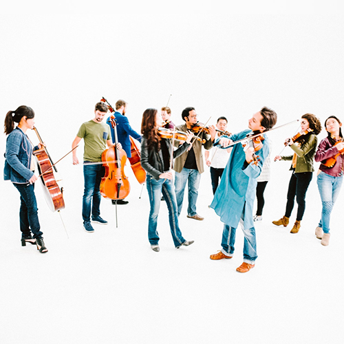 Photo of a modern day strings ensemble performing in street clothes.
