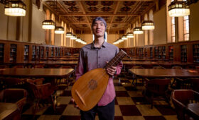 USC Thornton student holding a lute in an empty library.