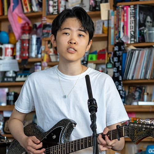 Photo of NoSo playing their electric guitar on the set of a television show.