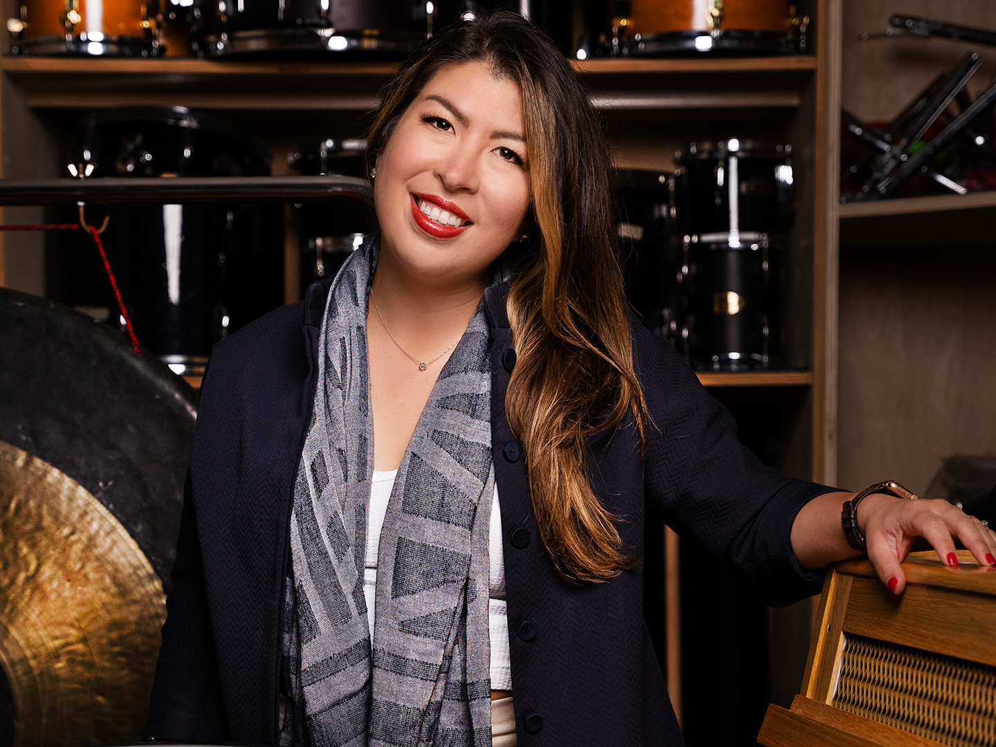 Michelle Simonsen dressed in concert attire smiling and posing next to percussion equipment. 