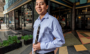Photo of a clarinetist holding his instrument outside in downtown Los Angeles.