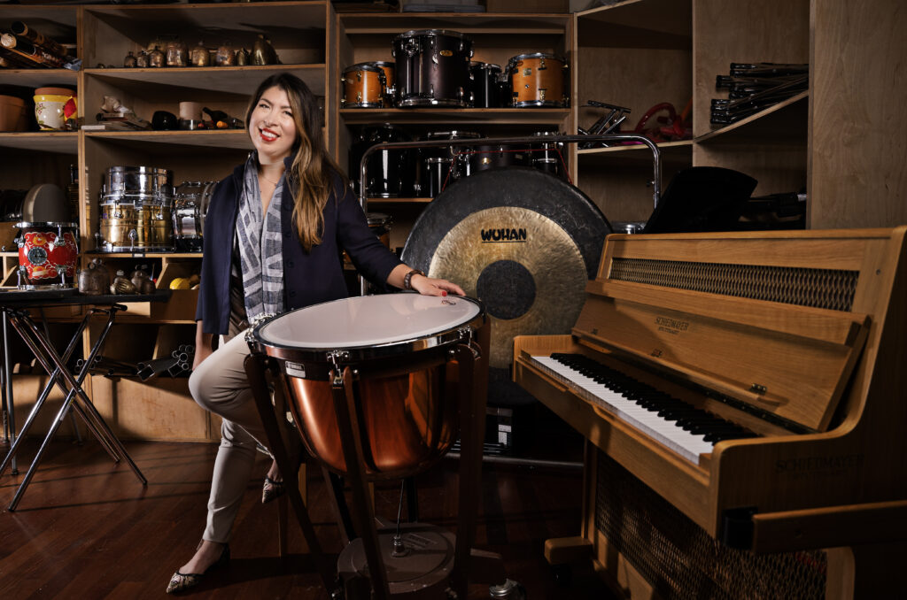 Photo of a classical musician posing next to percussion instruments.