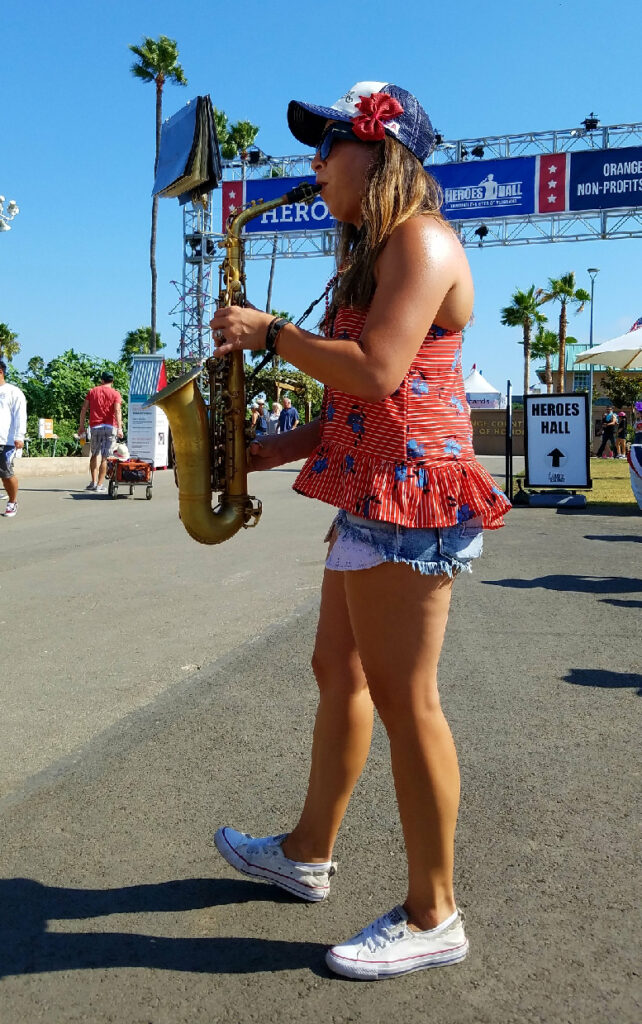 Photo of Michelle Maestas Simonsen playing saxophone outside.