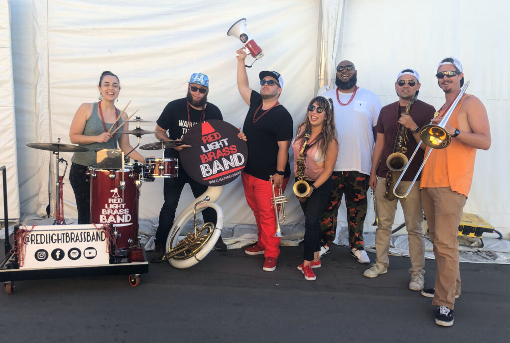 Photo of a brass instrument band with drums and Michelle Maestas Simonsen.