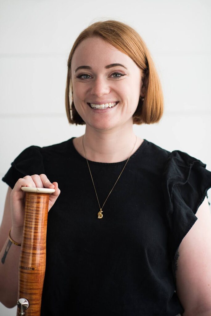 Photo of bassoonist Anne Ranzani smiling and holding her instrument wearing concert black attire.