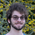 USC Thornton student Theodore Strich standing outside in a garden with flowers.