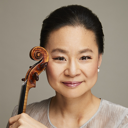 Photo of concert violinist Midori holding a violin and smiling.