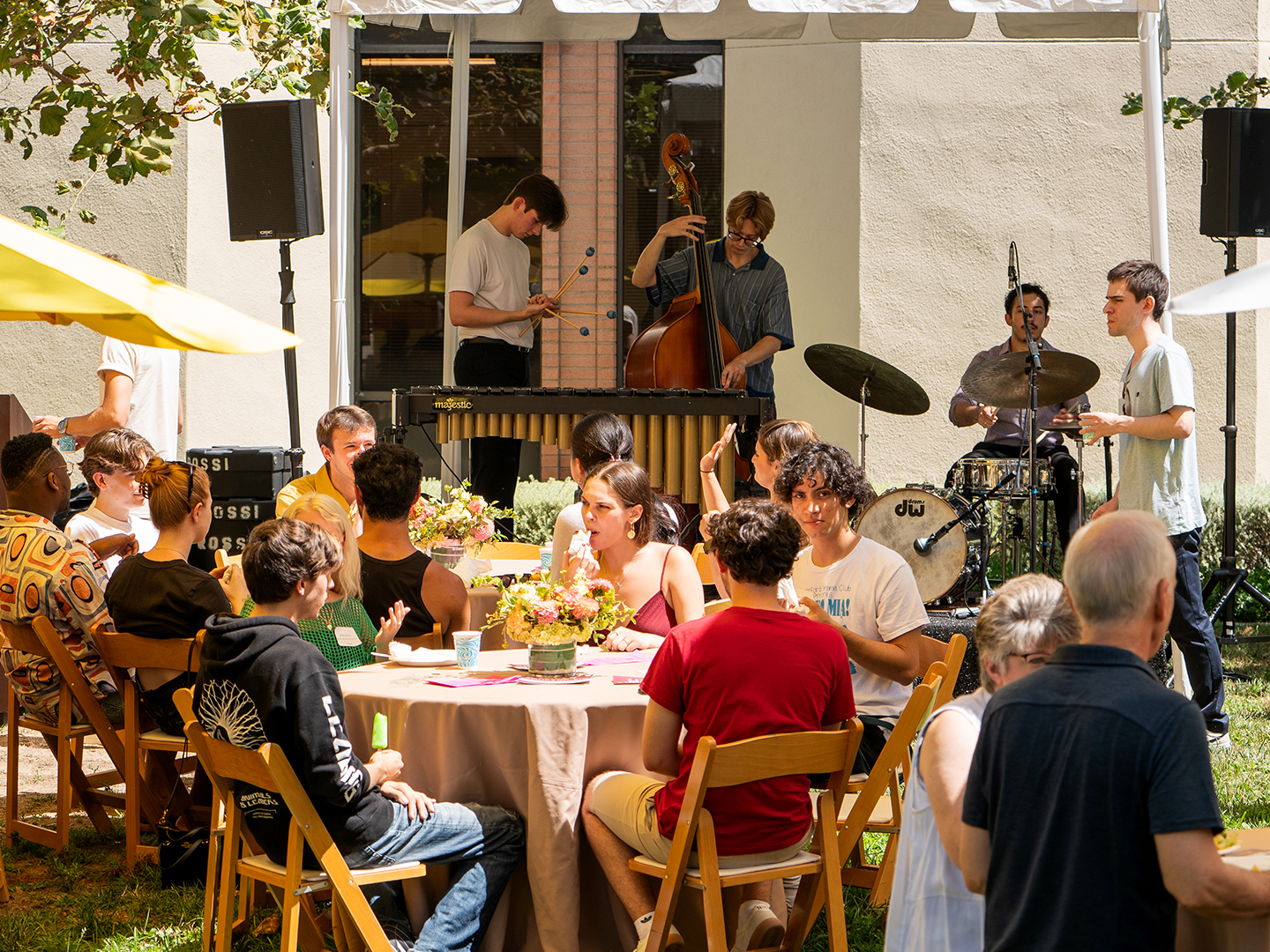 Students gathering outside under colorful tents for a academic event. 