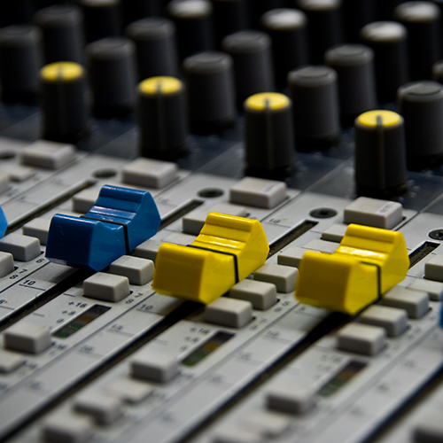 A mixing board with blue and yellow colored fader switches.