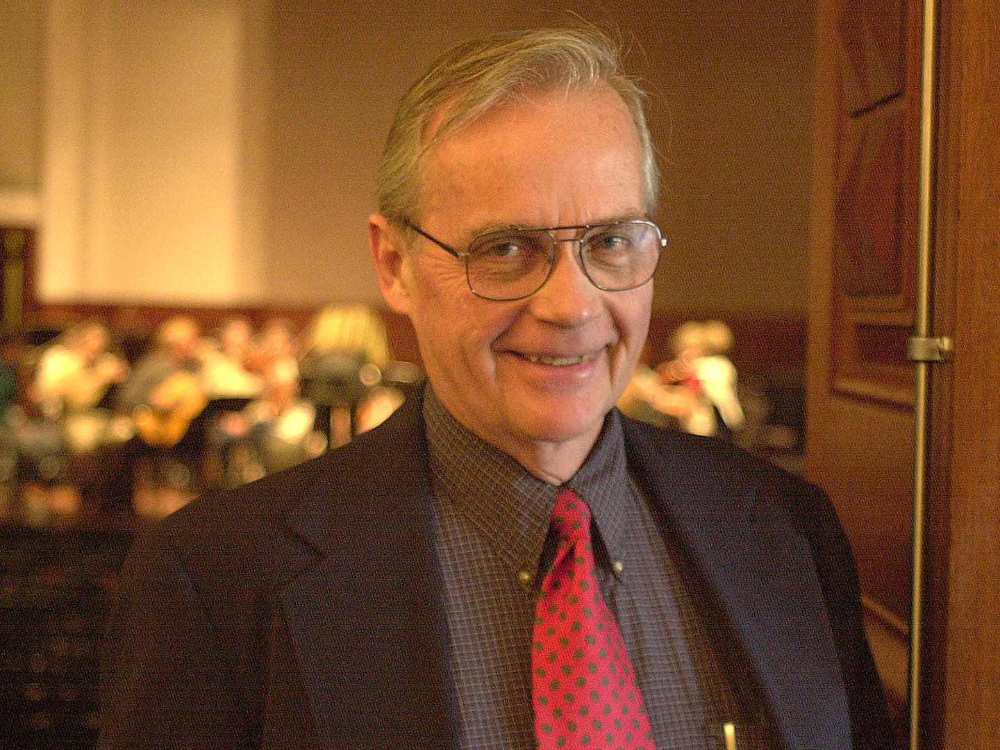 Photo of composer and teacher Rick Lesemann wearing a suit and tie and smiling at the camera. 