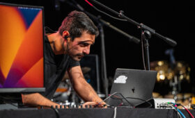 A composition student leans over a computer onstage to control sound.