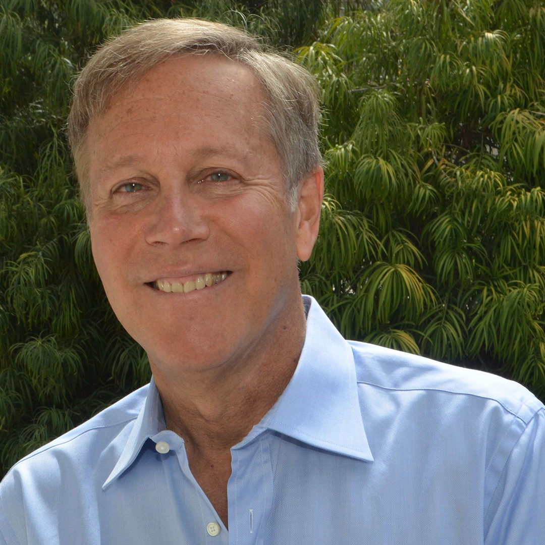 Dana Giois smiling outdoors next to a tree.