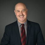 Composer and instructor Steve Rothstein smiling and wearing a dark suit.