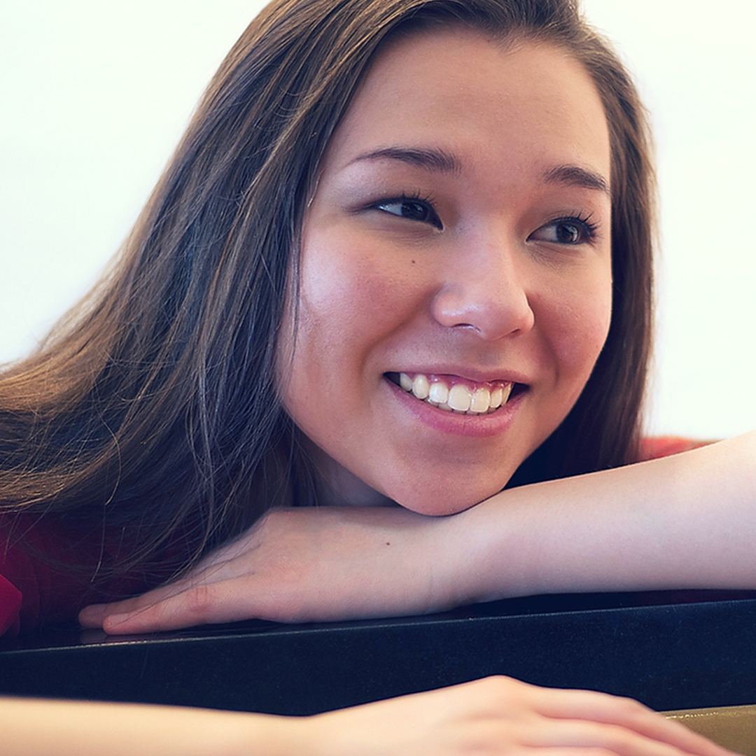 Pianist Elise Solberg with her piano, smiling.