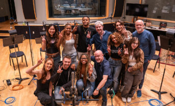 Photo of a group of smiling popular music students in a recording studio.