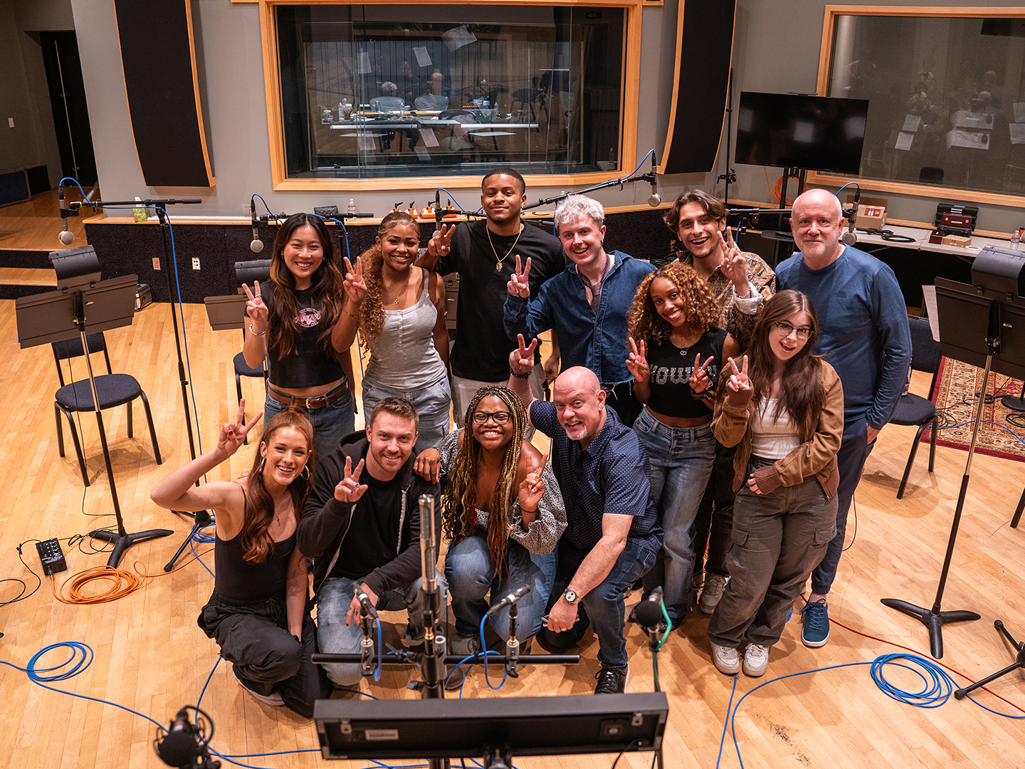 Photo of a group of smiling popular music students in a recording studio. 