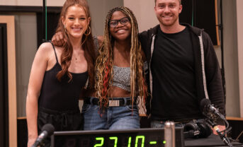 A trio of popular music songwriters and performers smile together for a posed picture in a modern recording studio.