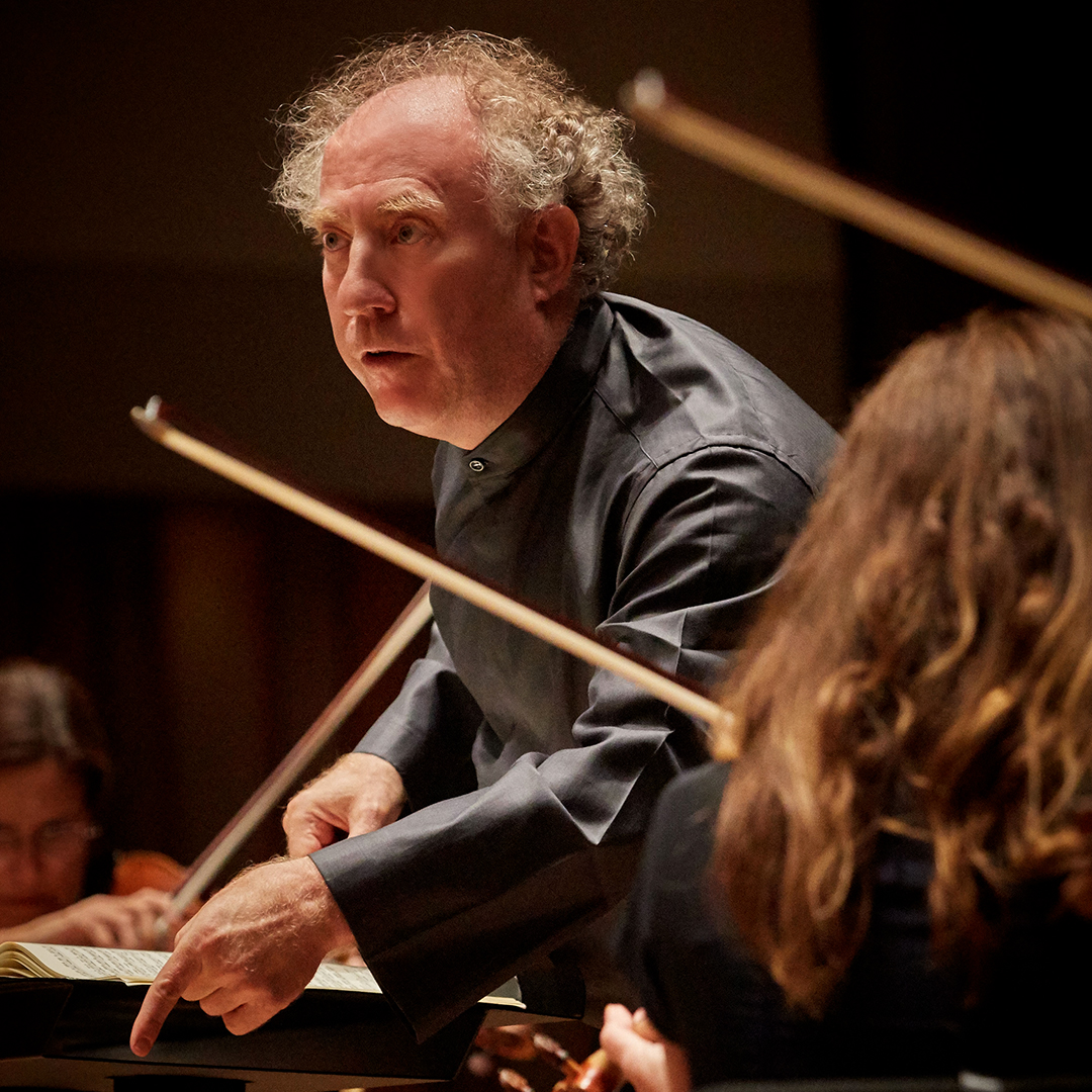 Conductor leading a classical ensemble on stage.