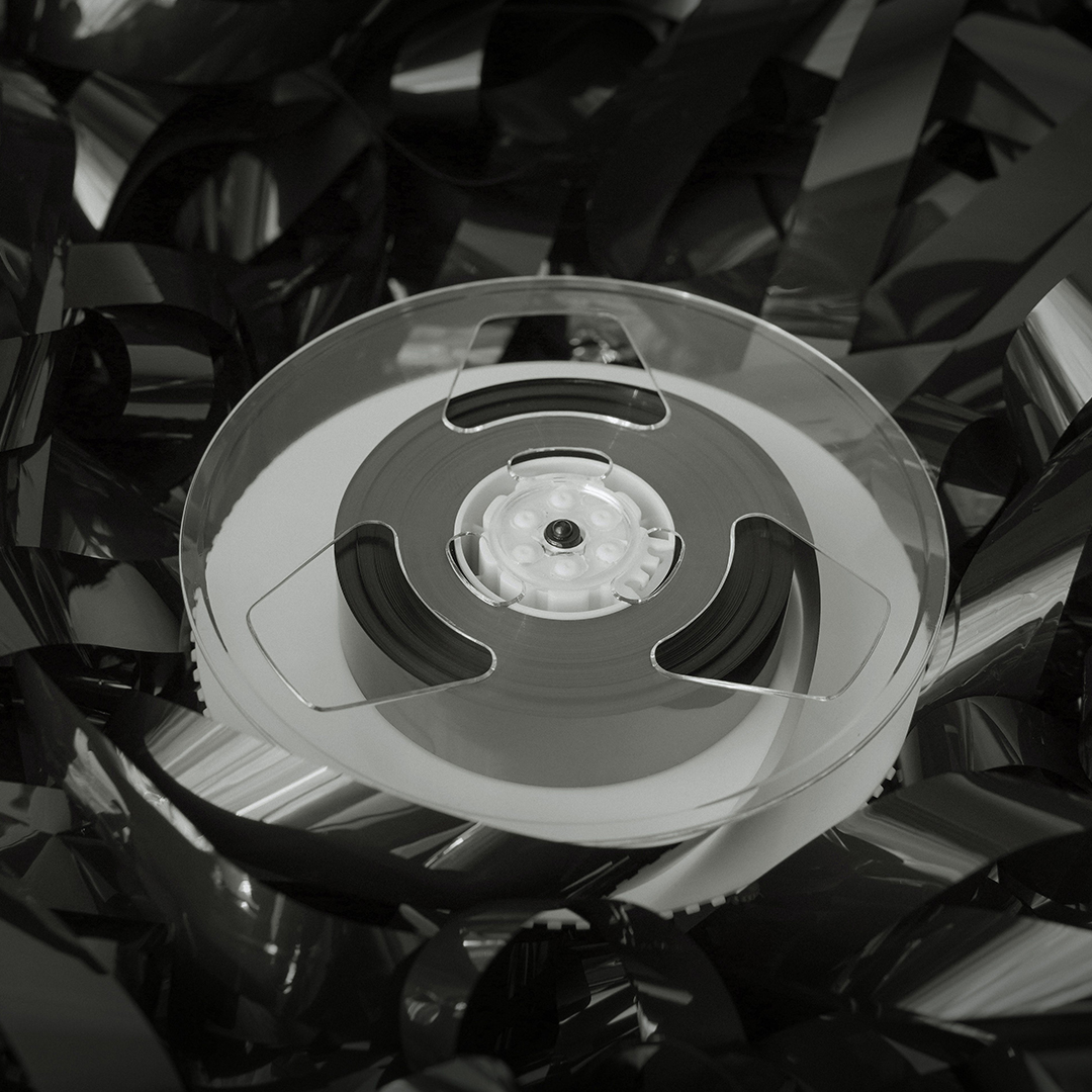 Black and white photo of a roll of unspooled audio tape for motion pictures.