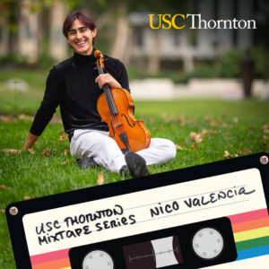 A viola student sits on the grass of a collage campus smiling and holding their instrument.