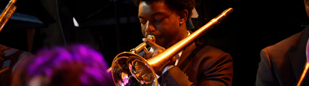 A student trombone player performs on stage.