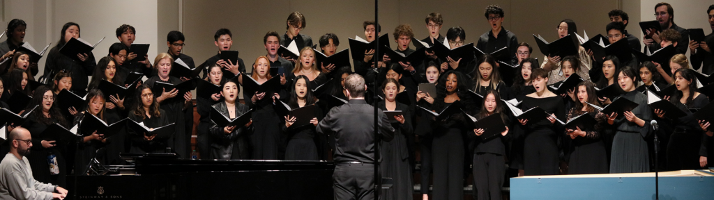 Photo of a choir dressed in concert black performing indoors.