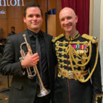 A musician holding a trumpet standing next to someone in a military uniform.