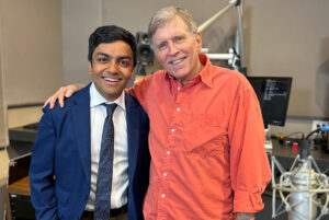 A radio host smiles with their guest in the recording studio.