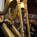 Two harp players on stage with the USC Thornton Symphony